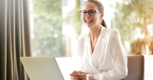 Online Business - Laughing businesswoman working in office with laptop