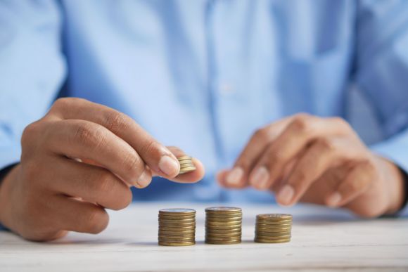 Investment - a person stacking coins on top of a table