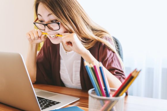 Start Up Business - woman biting pencil while sitting on chair in front of computer during daytime