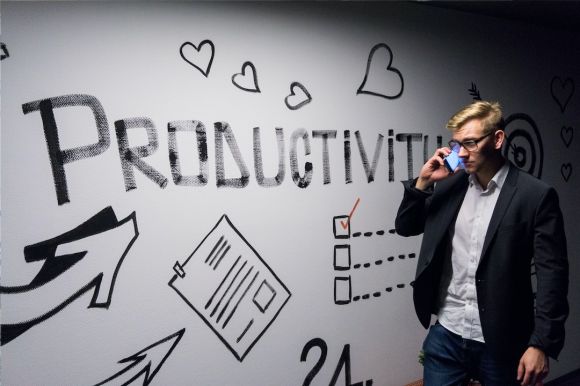 Entrepreneurship - man holding smartphone looking at productivity wall decor