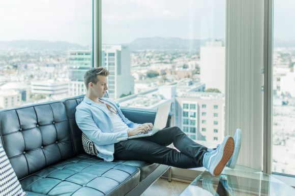 Online Business - man sitting on sofa while using laptop